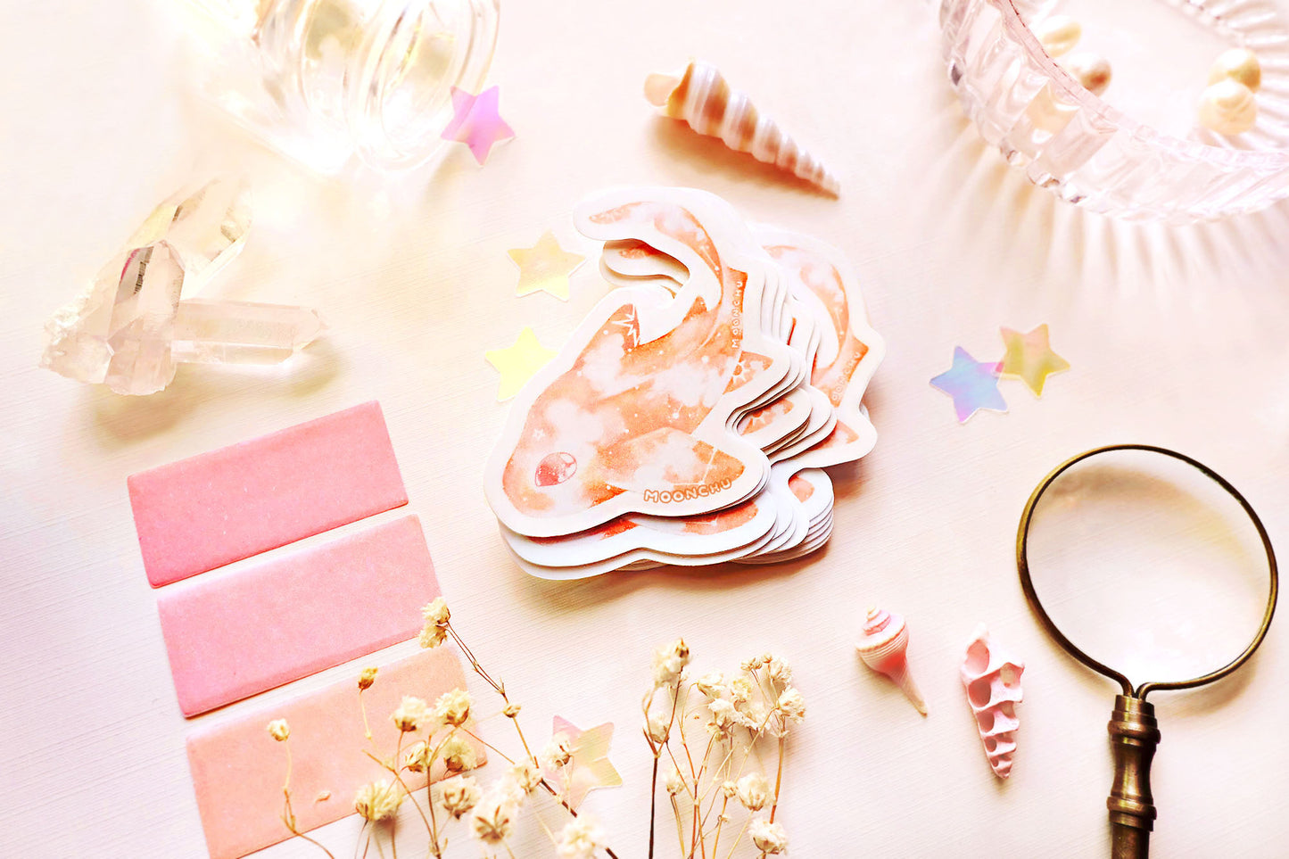original art illustrated sticker by moonchu depicting a watercolour painted leopard shark! with a pretty pastel orange body and little constellations. has a very cute eye and curved tail. pastel flatlay consists of other ocean items, like little shells and pearls. a high quality vinyl sticker for shark lovers or ocean gifts. perfect sticker for shark week.