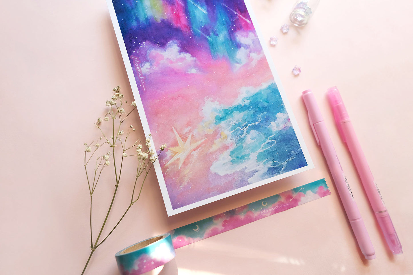 photo showcases a high quality art print of an original ink and watercolour ocean sky painting by moonchu. the illustration is very colourful with aurora and stars falling upon an ocean tide. a large, glowing star has fallen upon the beach. or washed ashore. up to you. sky gradients from purple to pink to light orange. a pretty dreamy art piece.