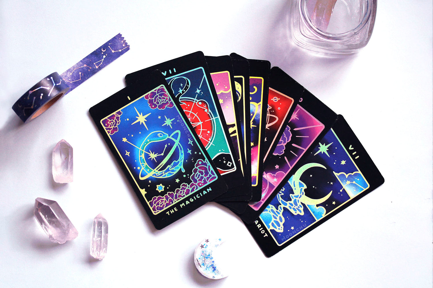 indie tarot deck by moonchu, all original art designs! featuring several magical nature and animal themed tarot cards. the magician is an ouroboros teal snake with a ring around him like a planet along with constellations. accented delicately and strategically with holographic foil. photo also depicts previews of other cards.