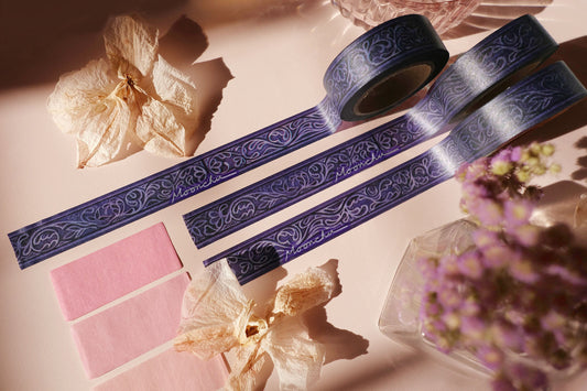 photo depicts original artist washi tape by moonchu. this design was created in watercolour, and transformed into washi tape for your journals, bujos, hobonichis, crafts, etc. it is a beautifully ornate design with swirls and leaves, swathed in a deep purple and navy background. the design itself is a light purple-ish colour. very art nouveau/filigree, large library with tons of amazing smelling books inspired. elaborate washi tape design.
