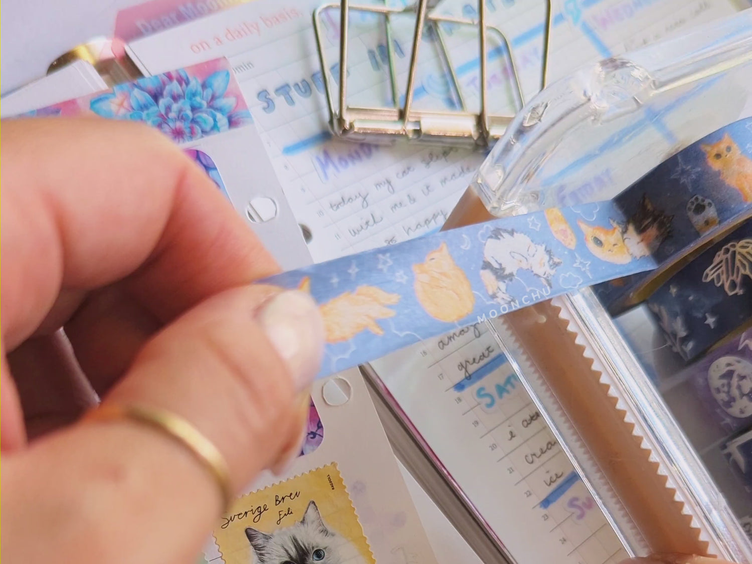 video showcasing original artist illustrated washi tape by moonchu (cut from a tape dispenser atop various journal pages and stationery items).