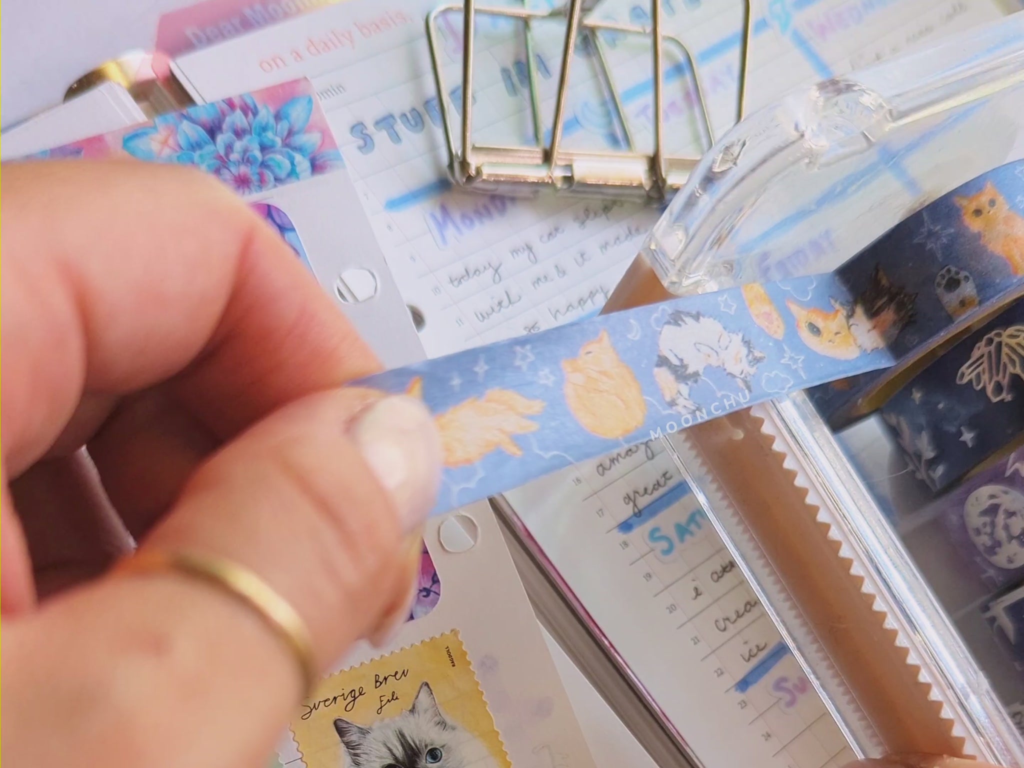 video showcasing original artist illustrated washi tape by moonchu (cut from a tape dispenser atop various journal pages and stationery items).