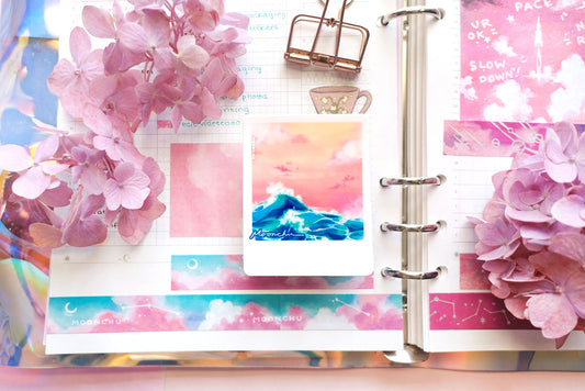 product image showcasing moonchu's original art sticker depicting a beautiful orange sunset and a teal wave with a white border, like a printed snapshot. a super glossy and saturated high quality vinyl sticker of ocean wave sunset. sticker sits atop a pretty journal spread with pink hydrangea flowers and other  moonchu unique stationery. a unique sticker for any ocean lover or beach goer. would look great on a water bottle that you take to the beach during the summer!