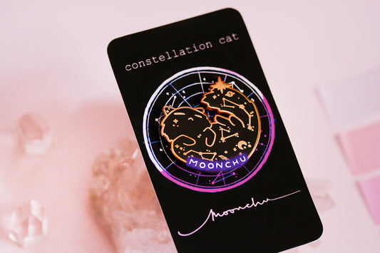 photo depicts original art by moonchu of a constellation space cat pin. rose gold hard enamel pin is of a black cat with constellations, little dipper, bat, and moon. a twinkling star perches upon its tail. a perfect gift for space lovers and cat lovers.